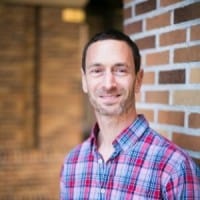 Expert male professional standing outdoors against a brick wall in Australia.